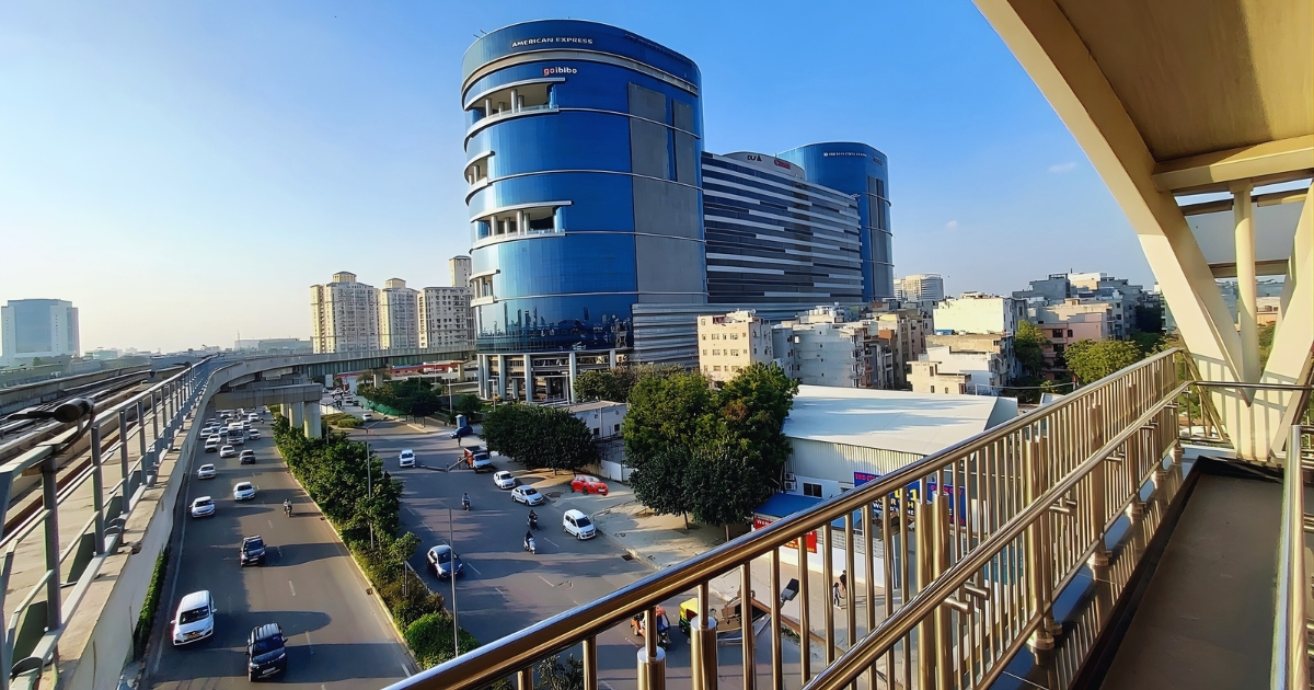 Modern glass commercial towers and metro line in DLF City, illustrating the premium infrastructure of one of the posh areas in Gurgaon.